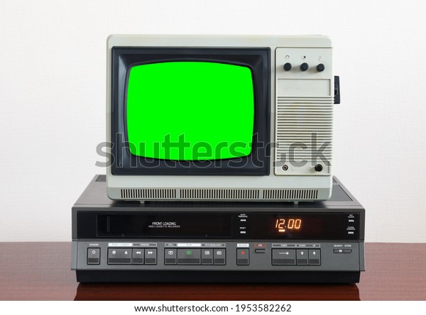Old silver vintage\
TV with green screen to add new images to the screen, VCR on\
wallpaper background.	