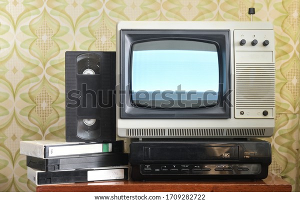 Old silver-colored TV with a VCR on the background\
of wallpaper.Screen noise.