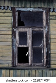 An Old Skewed Window With Broken Panes.An Abandoned Wooden House With A Skewed Window.Outdated Housing.