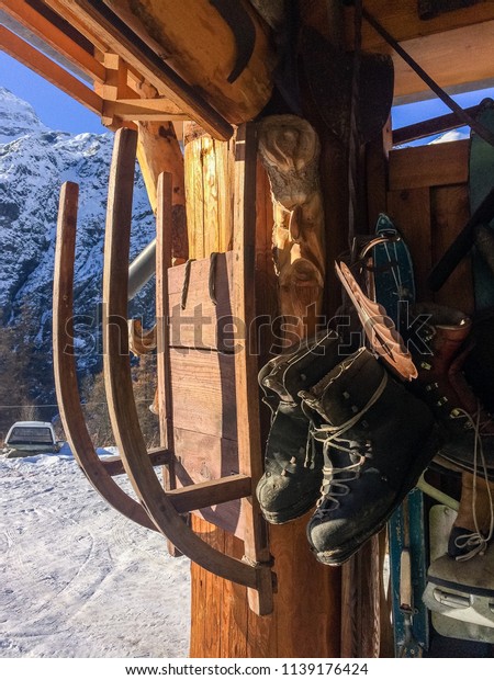Old ski tools and gears, skis, ice skate shoes,\
sled in an alpine chalet