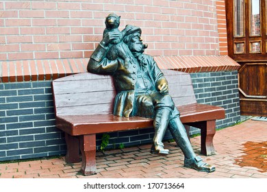 Old skipper with a monkey on his shoulder and a pipe resting on the bench. Fishing village, Kaliningrad, Russia