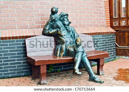 Old skipper with a monkey on his shoulder and a pipe resting on the bench. Fishing village, Kaliningrad, Russia