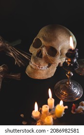 Old Skull And Candle With Incense On Old Altar Plate Which Has Dim Light. Select Focus, Black Background. Straw Voodoo Dolls. Copy Space Vertical Photo