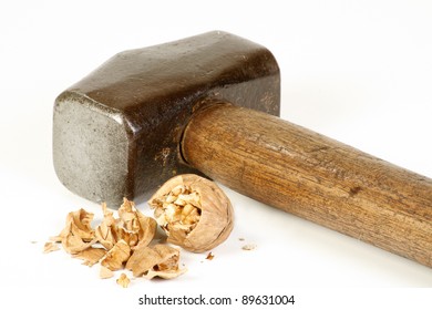 old sledge hammer and crushed walnut on a white background, excess force concept