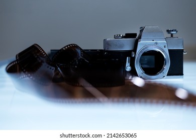 Old SLR camera and a used film on table light.