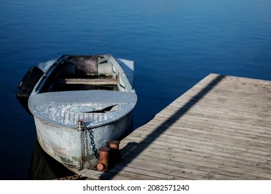 Old Small Boat Floating On The Lake Near The Pier.