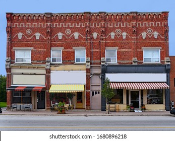 Old small town Victorian building with fancy brickwork and shops with awnings