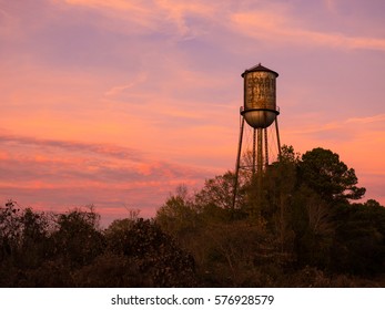 Old Small Town Water Tower Against A Brilliant Sunset Sky.