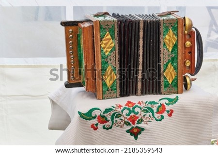 Old small vintage national Tatar accordion on white towel with traditional embroidery with floral pattern. National holiday Sabantuy