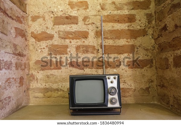 Old, small, vintage,\
retro television with antenna with old brick wall background.\
Vintage style photo.