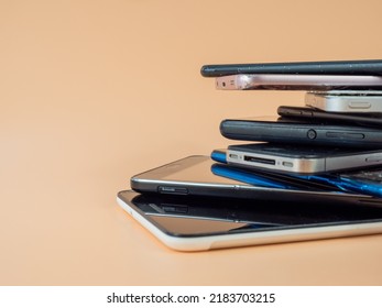 Old smartphones lie on top of each other. Stack of old mobile phones. Smartphones on an orange background. - Shutterstock ID 2183703215