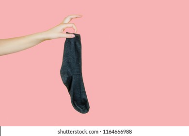 Old Smelly Holey Sock In Hand On A Pink Background