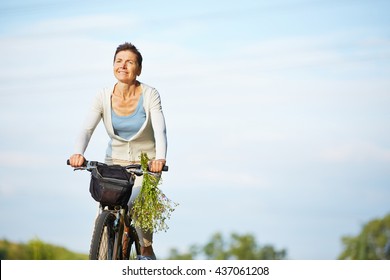 Old Smiling Woman Cycling With Her Bike In Summer