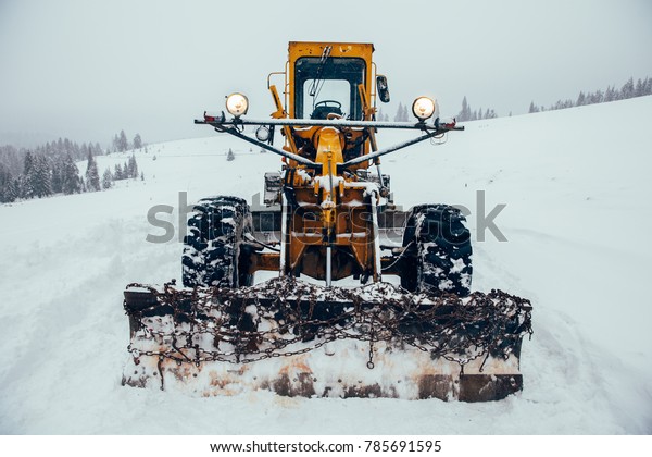 Old snow plow cleaning roads covered in snow\
up in the mountains.