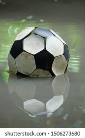 The Old Soccer Ball On Water Floor Reflected In Water.