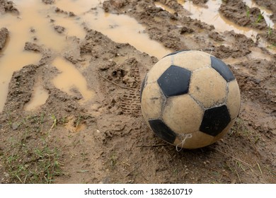 Old Soccer Ball On Wet Dirt Field