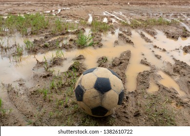 Old Soccer Ball On Wet Dirt Field