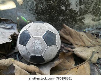 Old Soccer Ball Placed On A Leaf Near The Old Cement Water Tank.