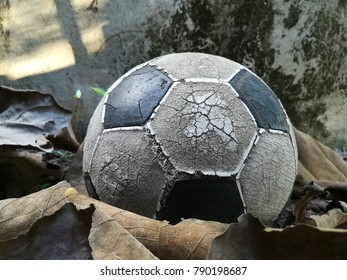 Old Soccer Ball Placed On A Leaf Near The Old Cement Water Tank.