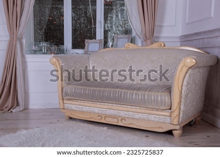 An old sofa with wooden planks by the window. Empire style furniture. Light white empty room interior. Divan couch in the living room