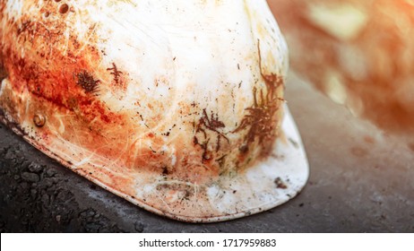 An old soiled white plastic safety helmet for an engineer or worker placed on a concrete block in a construction area. safety helmet and accident protection. broken helmet