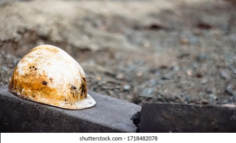 An old soiled white plastic safety helmet for an engineer or worker placed on a concrete block in a construction area. safety helmet and accident protection. broken helmet