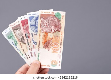 Old South African money - rand in the hand on a gray background