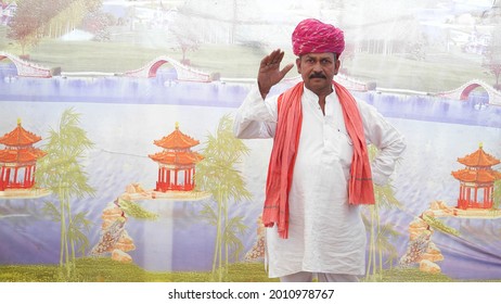 An Old South Asian Man Wearing A Traditional Costume And Saluting With His Hand
