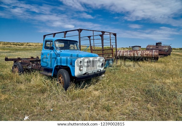 The old Soviet auto and agricultural machinery\
abandoned in the steppe not far from Sartymbet village, stone\
mountains \
