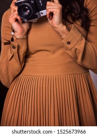 old soviet camera upside down in the hands of a girl in a brown dress