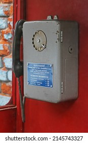 Old Soviet Telephone With A Warning Table About The Surcharge For A Long Call And With Emergency Phone Numbers (written In Russian) Hanging In Booth