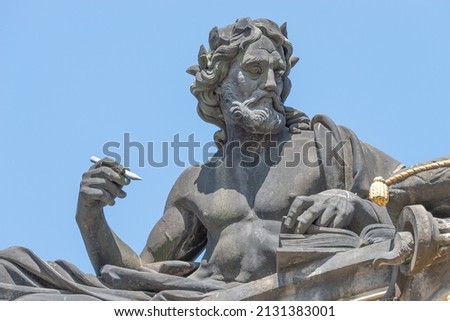 Old statute of poet or writer with book, Bible, writing something at historical center of Dresden, Germany, at blue sky