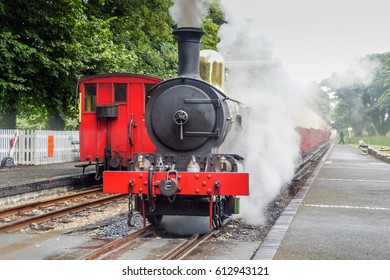 Old Steam Locomotive On Railroad Station. Retro Red Black Steam Train Front On Rail Station. Vintage Steam Railway Road Isle Of Man. Old Locomotive On Station UK Rail Travel.Vintage UK Train Travel