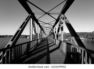 Old Steel Bridge Over Ruhr River At “Baldeneysee“ In Essen Germany. Former Railway Bridge With Symmetric Rivet Construction Today Is For Pedestrians And Bikers. Black And White Greyscale, Wide Angle.