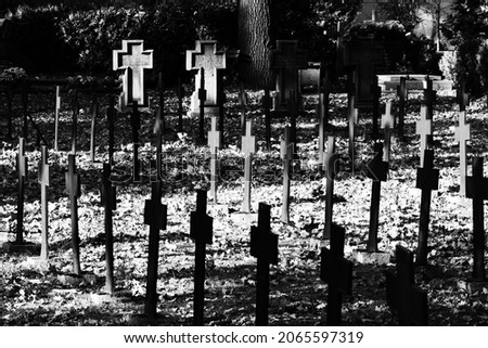 Old steel cross in a cemetery with a WW1 military man in black and white.
