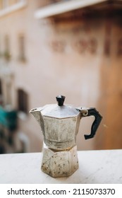 Old Steel Italian Geyser Coffee Maker On A Marble Windowsill. Moka Pot Closeup. Coffee Prepared In A Geyser Coffee Maker Is Cooled In The Window