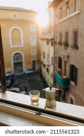 Old Steel Italian Geyser Coffee Maker On A Marble Windowsill With A Cup Of Hot Espresso With Milk. Coffee Prepared In A Geyser Coffee Maker Is Cooled In The Window. Morning Coffee Routine In Italy