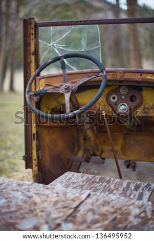 Old steering wheel and broken windshield of a rusting truck on a farm