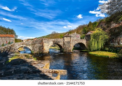 Old stone bridge over the village river. River bridge in summer. Rural river bridge. Medieval stone river bridge