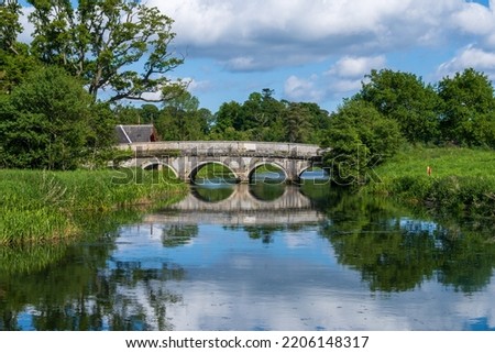 old stone bridge reflecting in a still river in green Irish countryside in spring