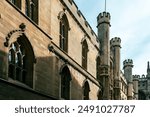 An old stone building with arched windows and turrets.  Cambridge, UK.