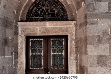 old stone building entrance door made of wood, brown painted, metall shutters and frame - Powered by Shutterstock