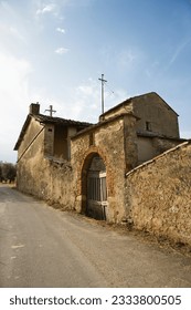 Old stone buillding in state of disrepair with arched gated entrance in Tuscany.