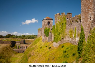 The old stone castle overgrown with greenery on the blue sky background.