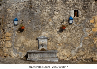 Old stone fountain dated 1811 on a rustic wall in an Italian village, decorated with lanterns and flower pots, evoking timeless charm - Powered by Shutterstock