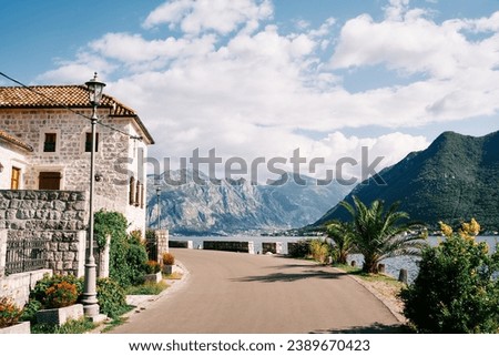 Old stone mansion with a green garden at the turn of the road above the sea. Perast, Montenegro