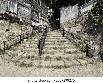 Old stone stairs. An old stone staircase outside and grass among the stones. Old antique stone stairs in nature. Stone staircase steps with black iron fences among old houses. Close-up. - Powered by Shutterstock