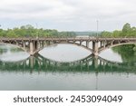 Old stone street bridge reflection over water. Photo taken at Lady Bird Lake in Austin Texas on a cloudy day