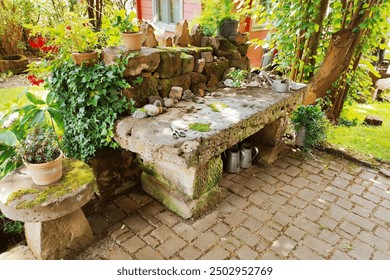 Old stone table under a tree. Flowers in a pot in a garden in sunlight in summer.  - Powered by Shutterstock