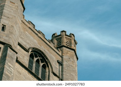 An old stone tower with an arched window against a light blue sky in Cambridge, UK. - Powered by Shutterstock